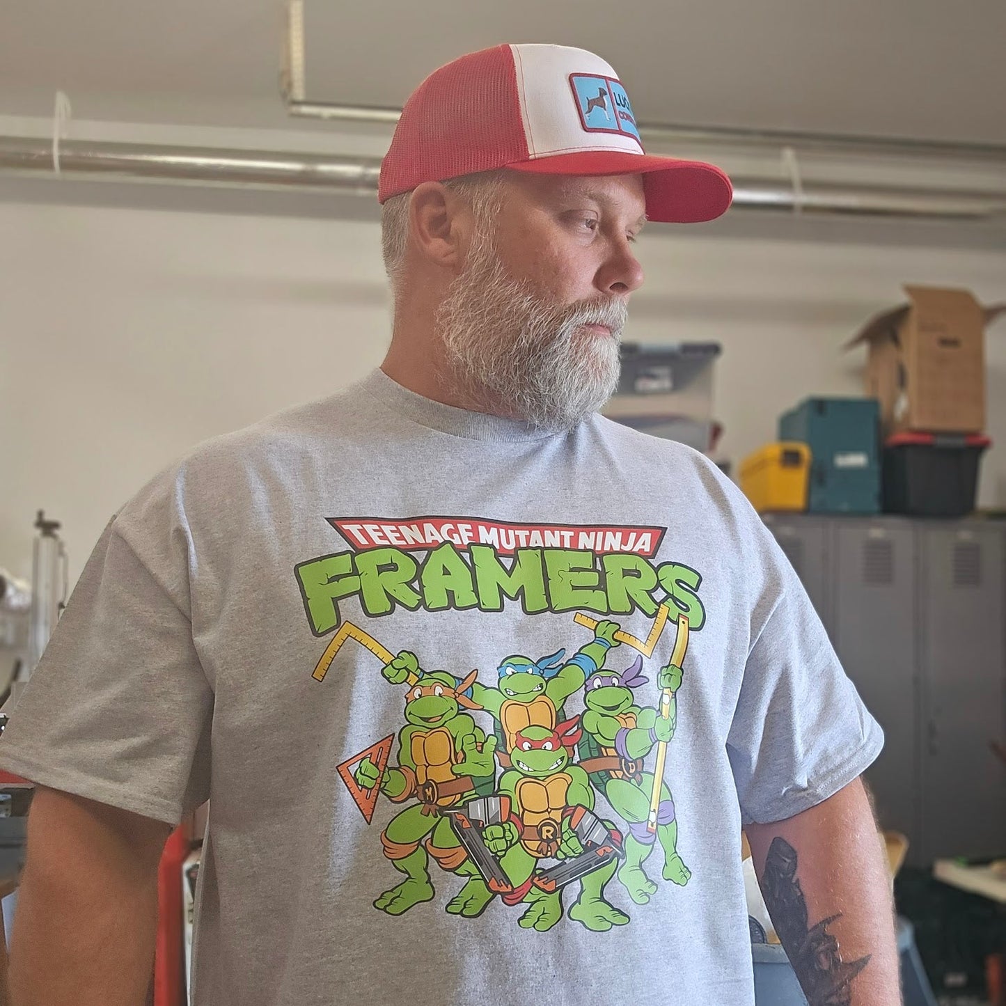Man wearing a gray t-shirt with a graphic design and a red and white cap in an indoor setting.