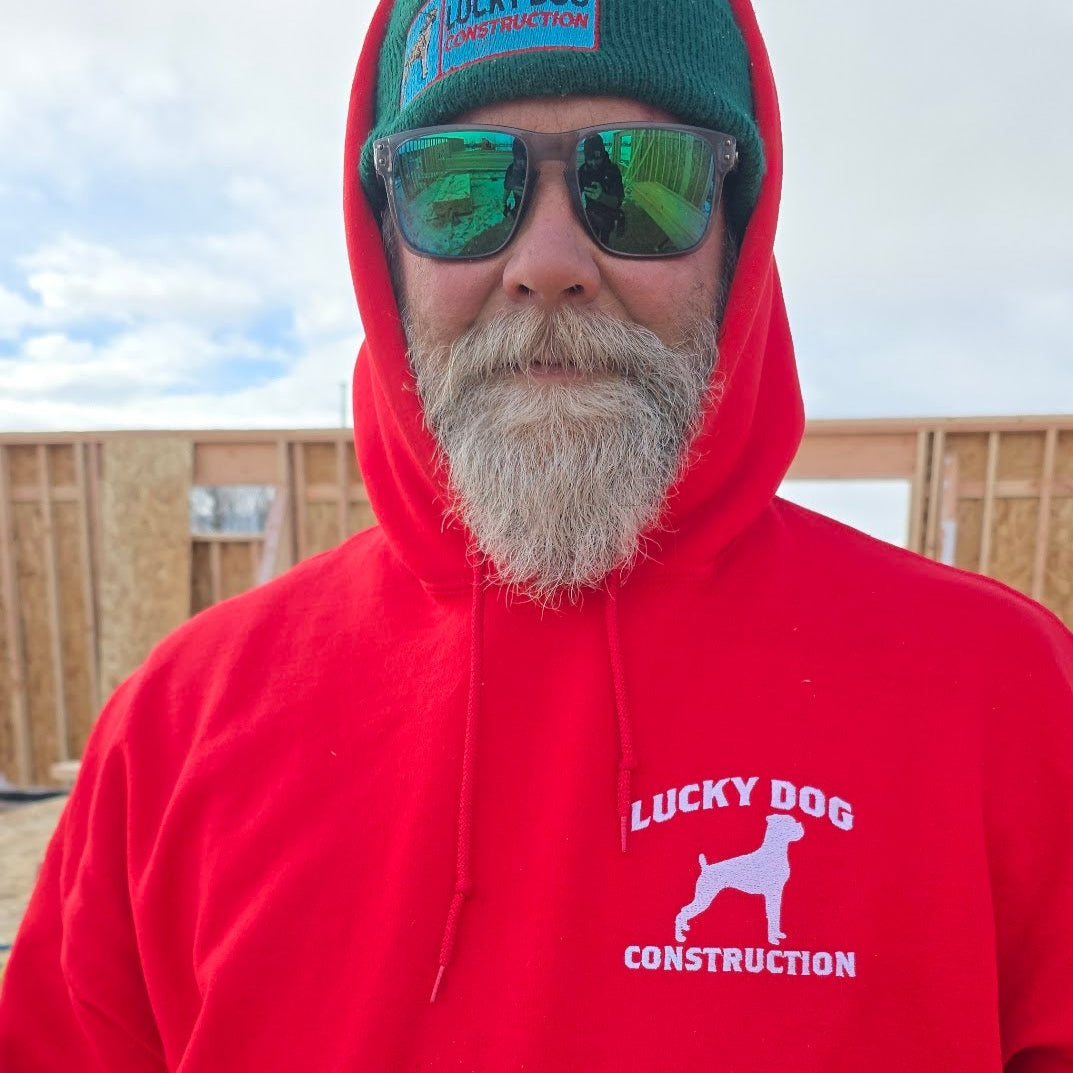 Man wearing a red 'Lucky Dog Construction' hoodie with sunglasses and a green cap.