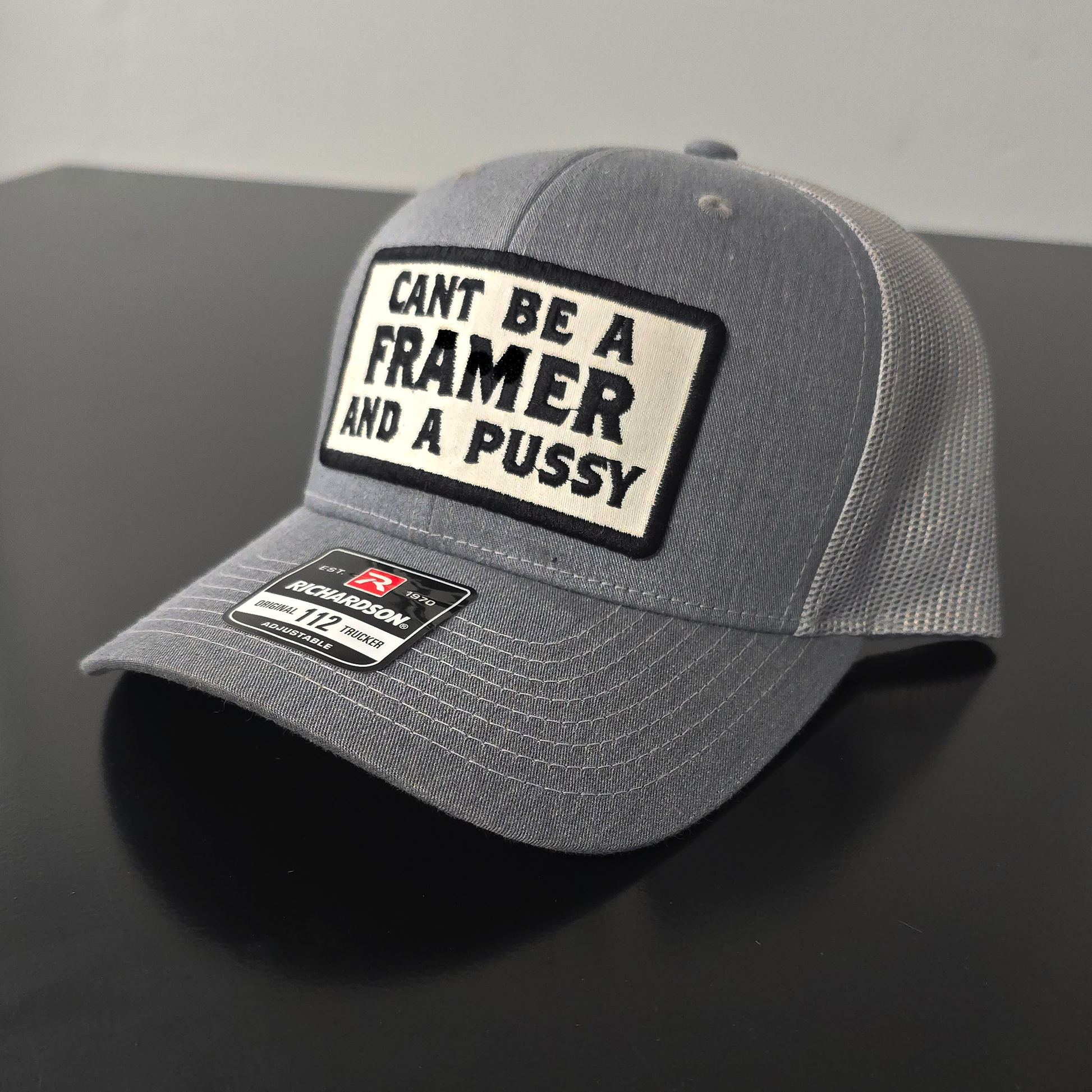 Gray cap with a black and white patch on a dark surface